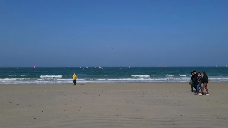 Trestraou Beach Perros-Guirec with numerous colorful sailing dinghies on water and kite surfers in distance