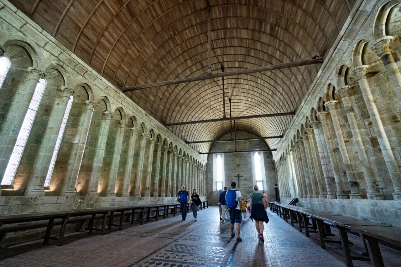 Mont Saint-Michel abbey refectory with wooden barrel vault ceiling and stone walls with arched windows