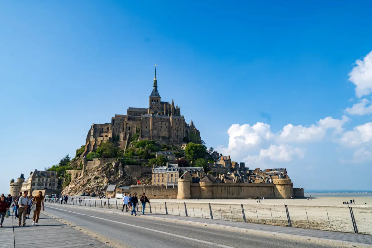 Mont Saint-Michel abbey view from Passerelle bridge exit with tourists walking away