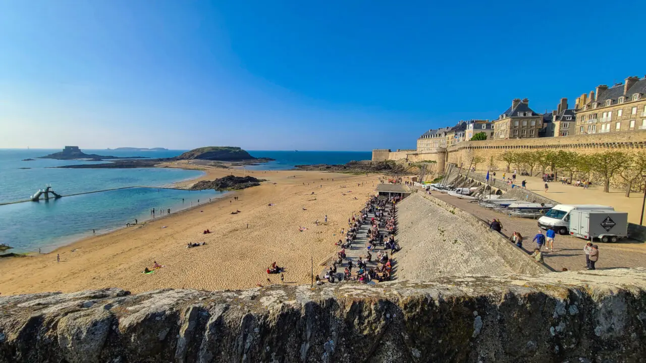 View from Saint-Malo ramparts overlooking busy Plage de Bon-Secours beach with crowds of people