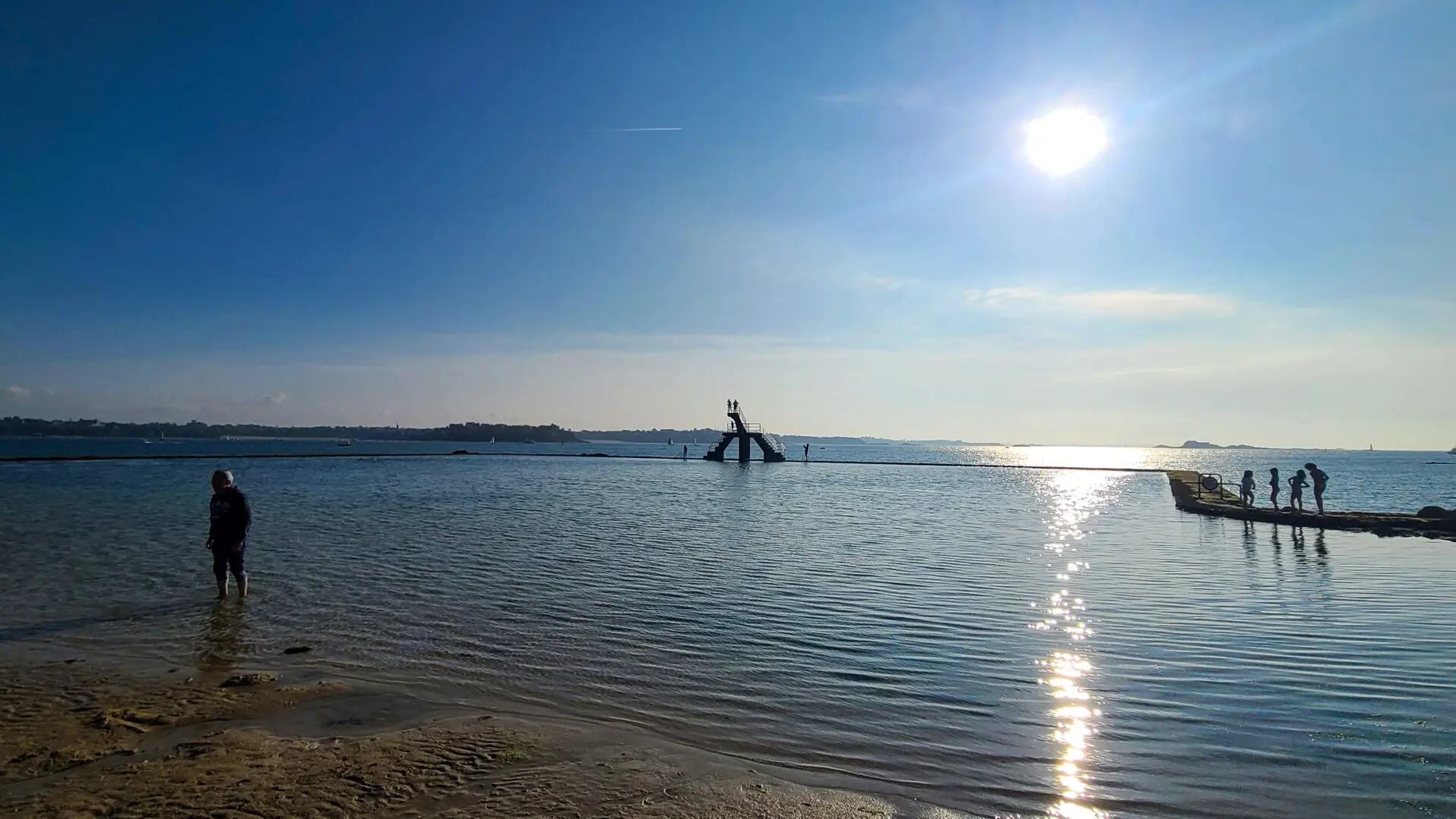 People on seawater pool and diving board at Plage Bon-Secours in Saint-Malo enjoying sunny day