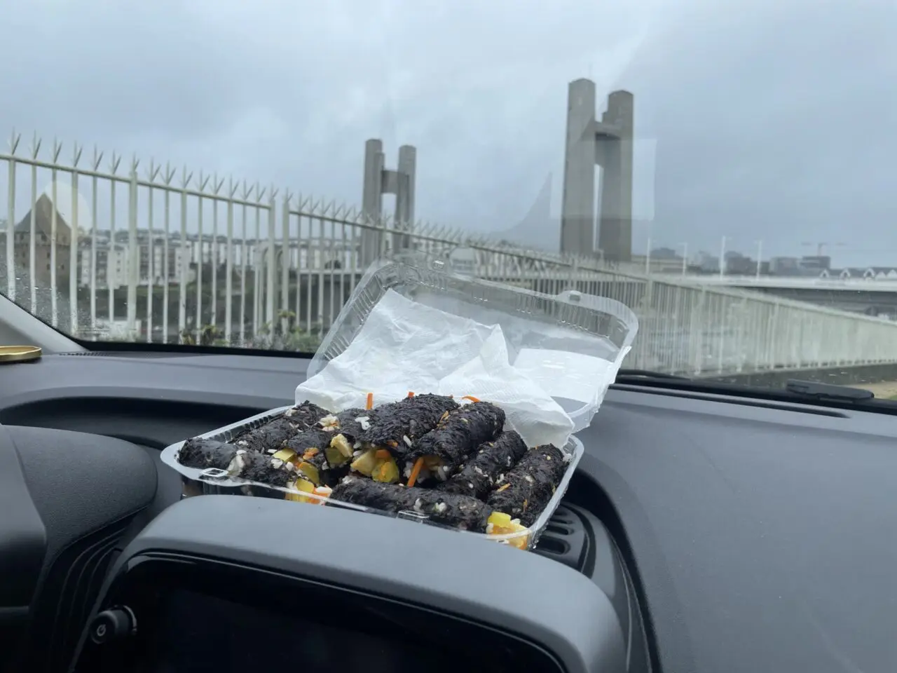 Torn homemade gimbap in car with Pont de Recouvrance bridge visible in background in Brest